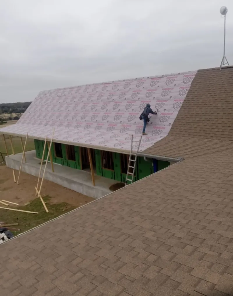 Worker preparing underlayment for a metal roof installation in Jefferson
